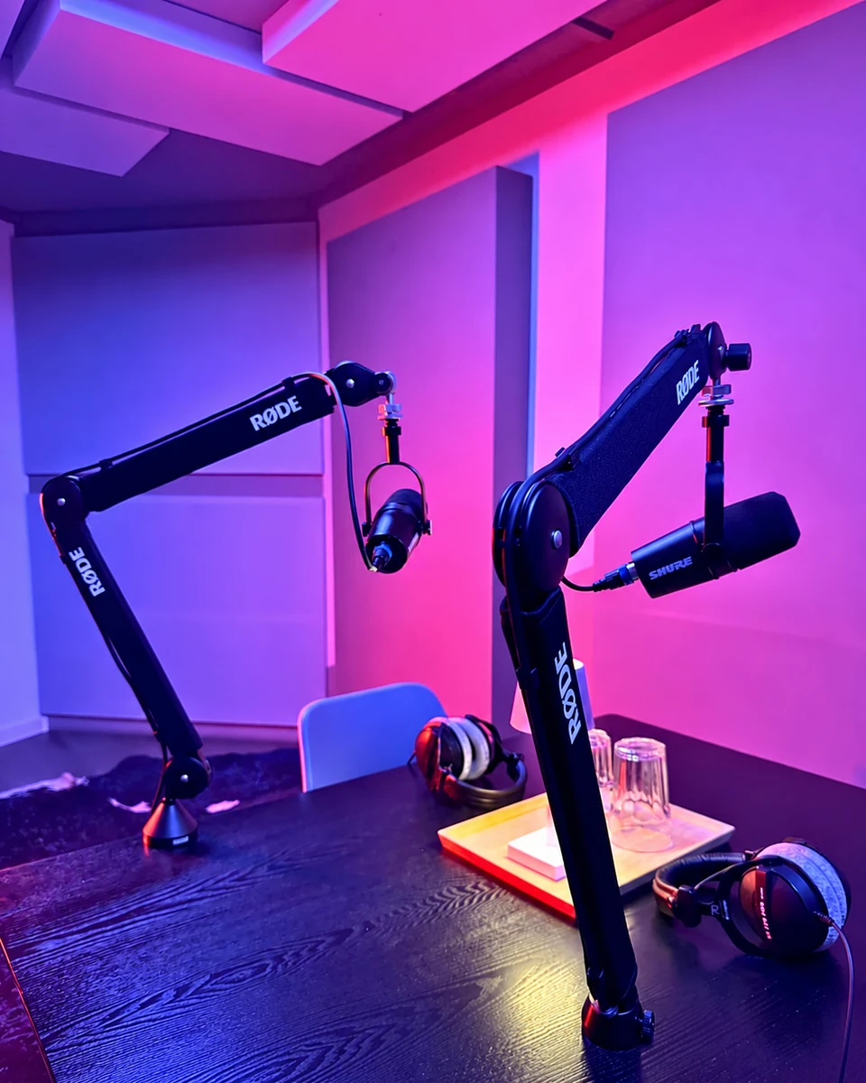 Zwei Mikrofone im farbig beleuchteten Podcast-Studio