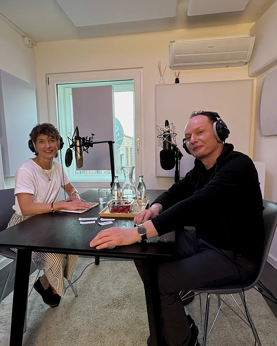 Zwei Gäste im Gespräch an einem Podcast-Tisch